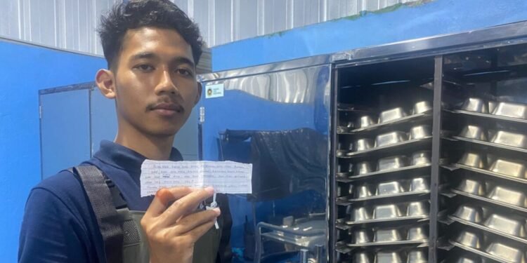Petugas Dapur SPPG Yayasan Sukaratu 6, Kecamatan Majasari, Kabupaten Pandeglang, memperlihatkan selembar surat cinta dari siswa yang terselip dalam ompreng MBG, Rabu 11 Februari 2026. (Dokumentasi Bantenraya.com)