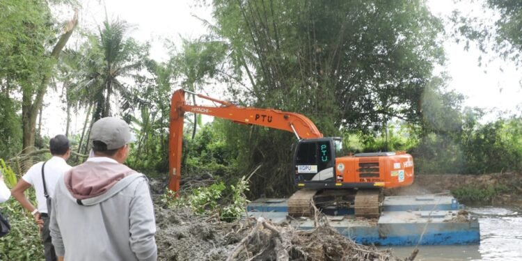 Petugas DPUPR Kabupaten Serang memantau normalisasi Sungai Cikambuy dengan menurunkan satu alat berat di Desa Cijeruk, Kecamatan Kibin, Rabu 11 Februari 2026. (Andika/Bantenraya.com)