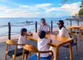 Suasana sebuah keluarga saat menikmati momen bersantai melihat pemandangan sunset ditemani deburan ombak di Harumi Kafe and Resto. (Dok/Hiromi Anyer)