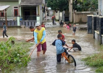 Warga dan anak-anak sedang bermain di lokasi banjir yang terjadi di salah satu desa, Kecamatan Bojonegara, Minggu 8 Maret 2026. (Andika/Bantenraya)
