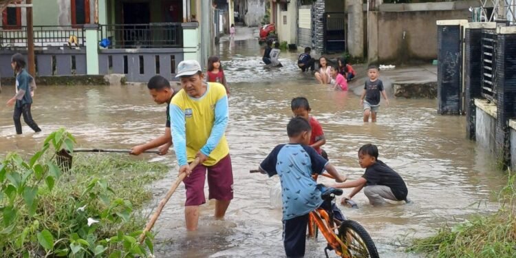 Warga dan anak-anak sedang bermain di lokasi banjir yang terjadi di salah satu desa, Kecamatan Bojonegara, Minggu 8 Maret 2026. (Andika/Bantenraya)