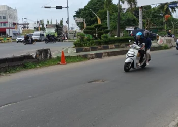 Pengendara motor menghindatri jalan berlubang yang ada di sekitar Kampus Merah Jalan Lingkar Selatan (JLS), Desa Serdang, Kecematan Kramatwatu, Minggu (1/3/2026). (Andika/Bantenraya.com)