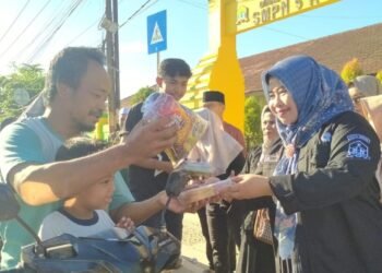 Kepala SMP Negeri 5 Kota Serang Ita Cahyawati membagikan takjil gratis kepada warga pengendara sepeda motor, Jumat 13 Maret 2026. Berbagi takjil di bulan Ramadan dalam rangka menanamkan nilai kepedulian sosial bagi siswa-siswinya. (Harir Baldan/Bantenraya.com)